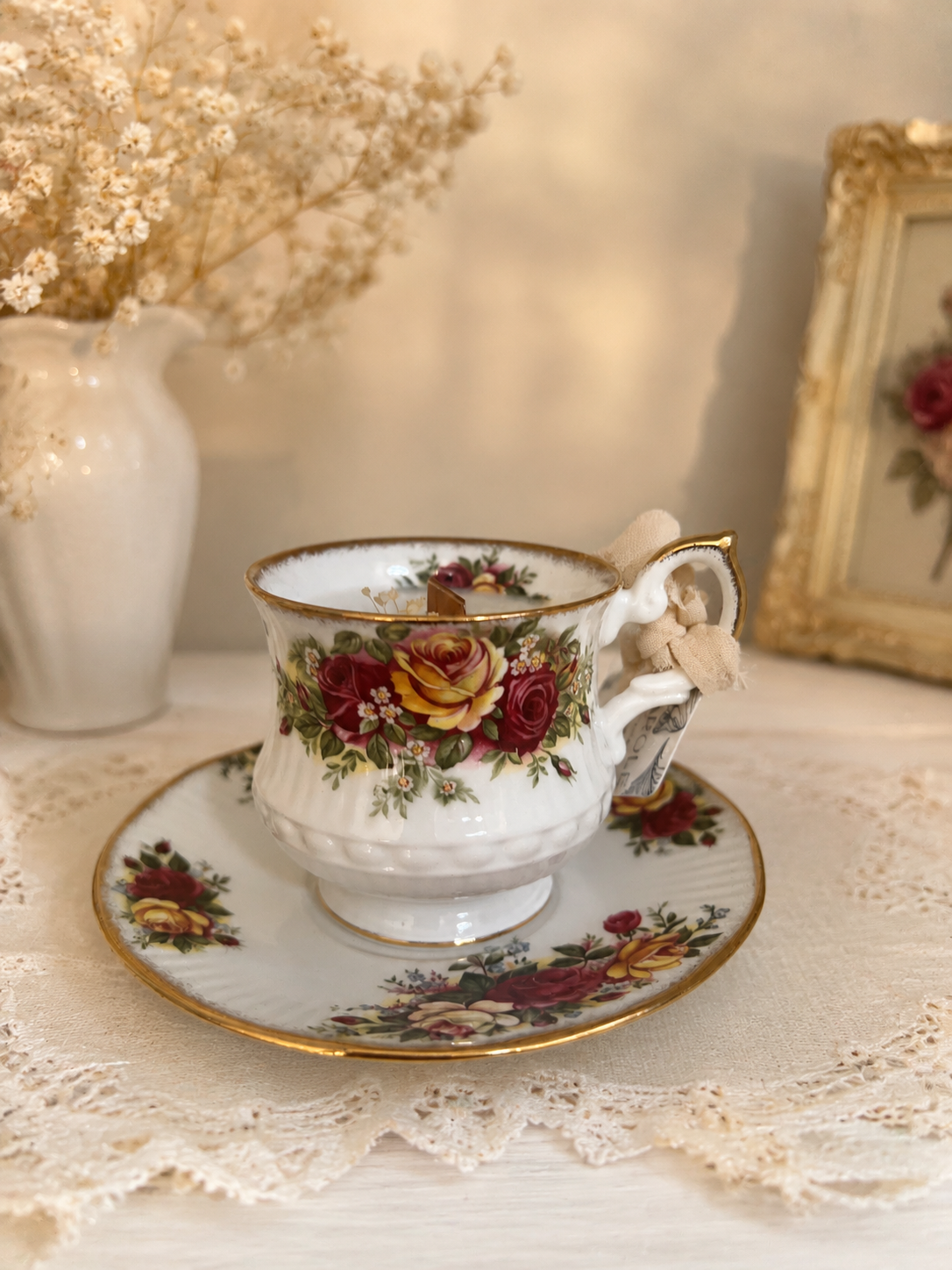 Candela in tazza vintage inglese con rose rosse e gialle e foglie