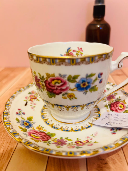 Candela in tazza vintage inglese con fiori colorati, bordi oro ondulati